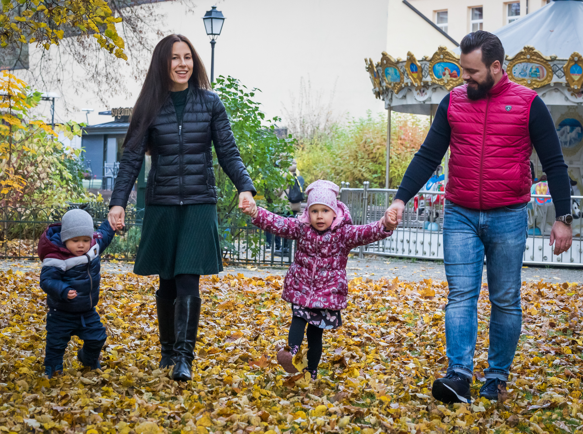 Tėtis ir mama parke su dviem mažais vaikais