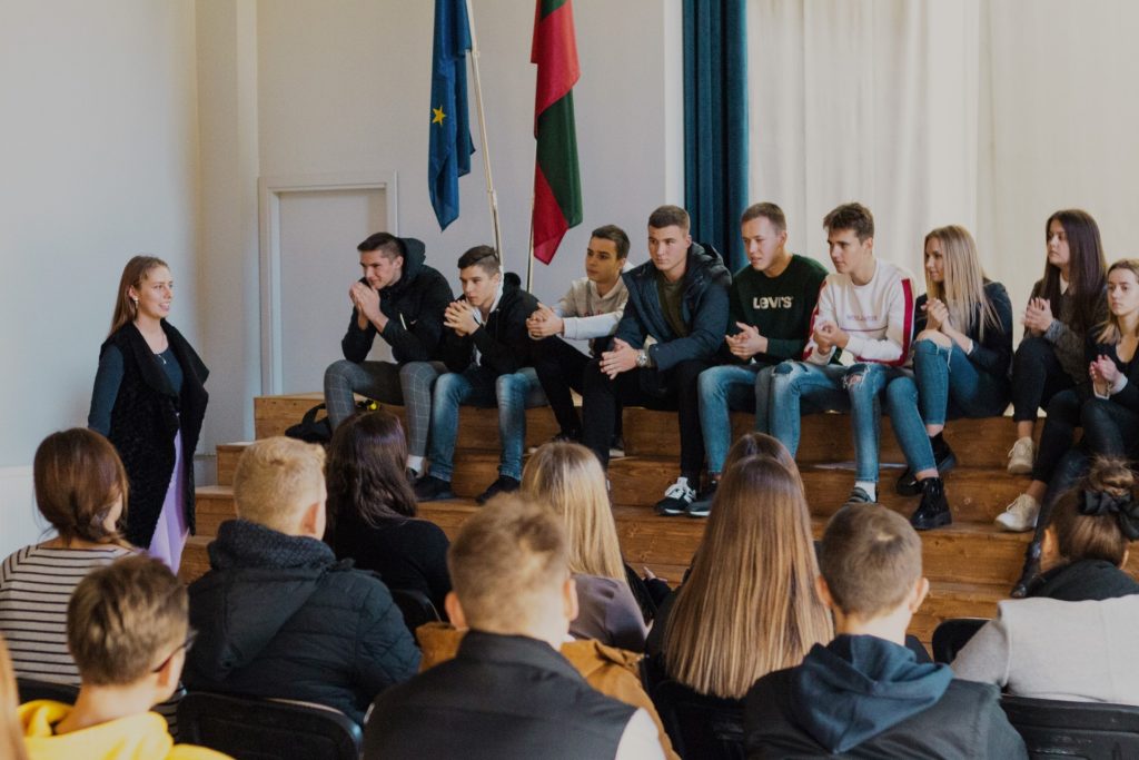 Ant scenos laiptų sėdintys mokiniai