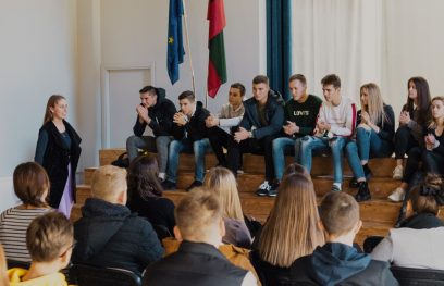 Ant scenos laiptų sėdintys mokiniai