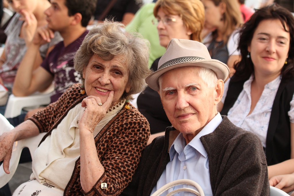 Vyresnio amžiaus moteris ir vyras žvelgia į objektyvą renginyje. Nicu Buculei nuotr./Flickr.com