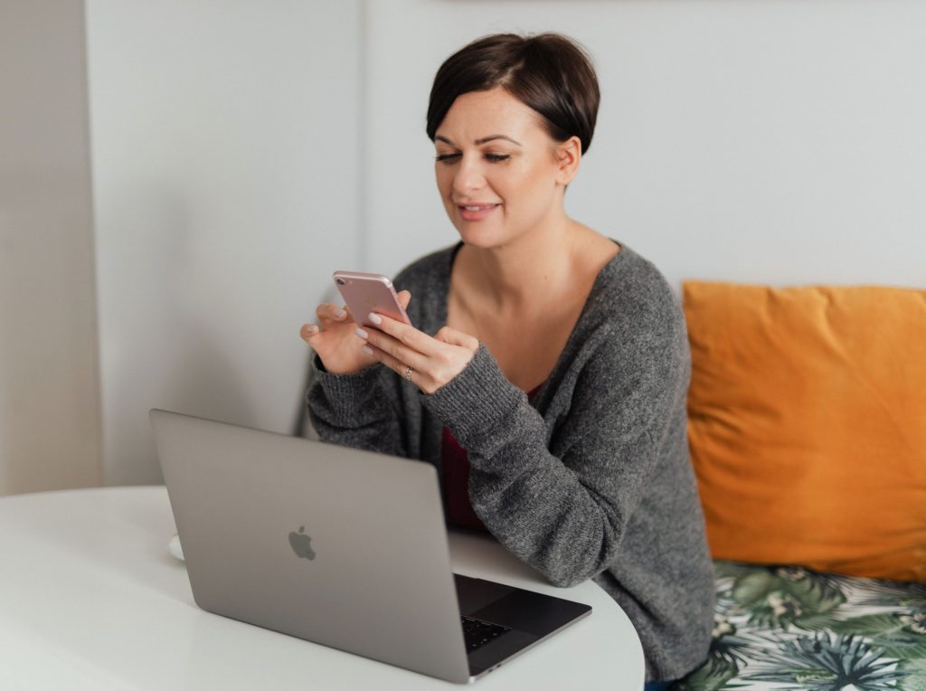 Moteris su mobiliuoju telefonu ir kompiuteriu. Pxfuel.com nuotr.