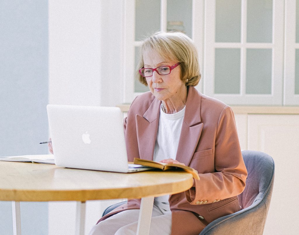 Vyresnio amžiaus moteris sėdi prie nešiojamojo kompiuterio. Pexels nuotr.