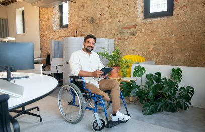 Vyras su negalia vežimėlyje, biuro aplinkoje. Pexels nuotr.