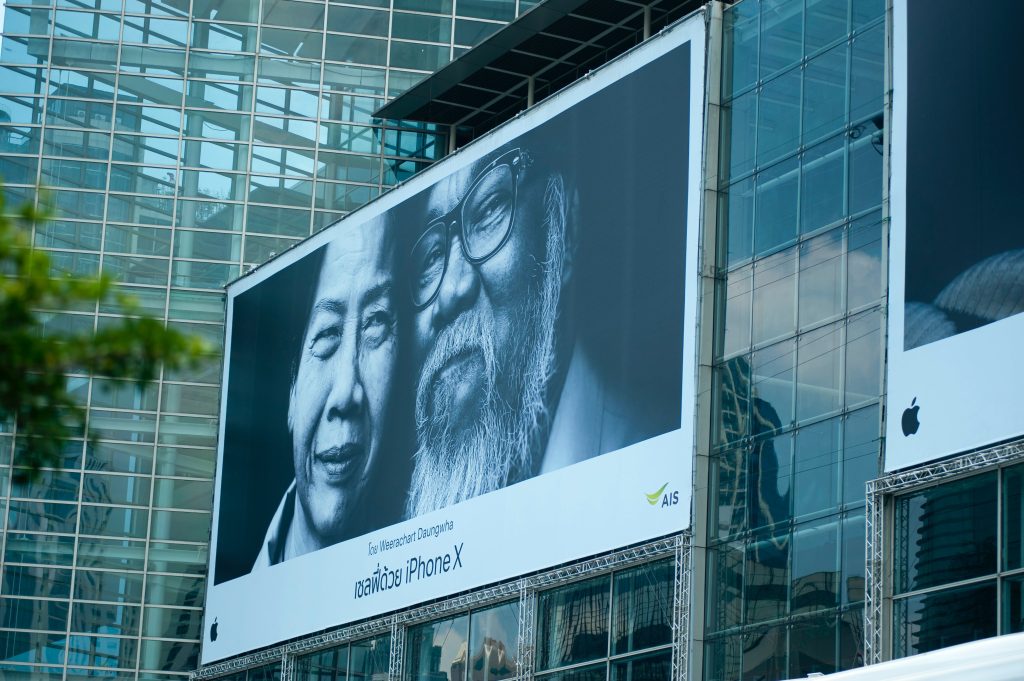 Vyresnio amžiaus žmonių fotografija reklaminiame stende ant pastato sienos